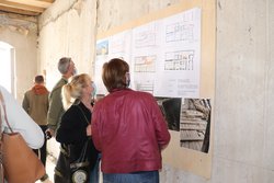 Das Foto zeigt die MdL Rosi Steinberger und Sabine Weigand, wie sie einen großen Plan an einer Wand begutachten.